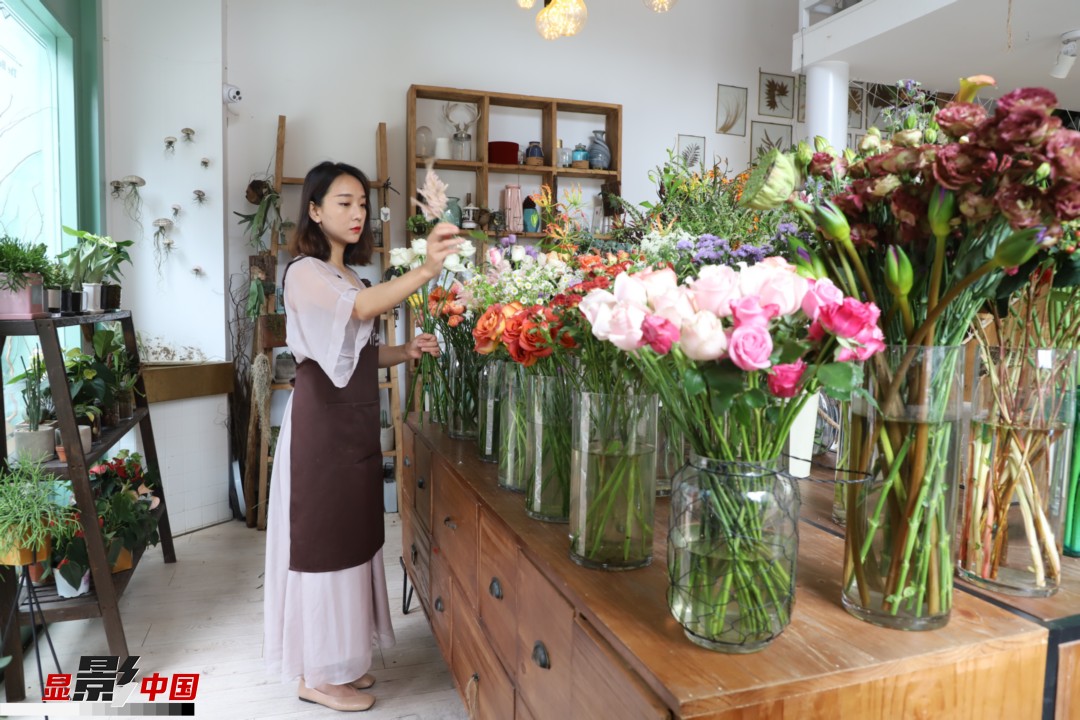 王黎媛是一名河南姑娘，在昆明念完大學后，就再也舍不下春城的藍天陽光、青山碧水，更舍不下這里的四時繁花，于是就干脆留了下來，成了一名媒體人。2017年的時候又毅然辭去工作，創(chuàng)業(yè)開起了花店，成了都市里的一名“花房姑娘”。圖為王黎媛在自己的花店中整理鮮花。新華網(wǎng) 周亞平/攝 念新洪/文